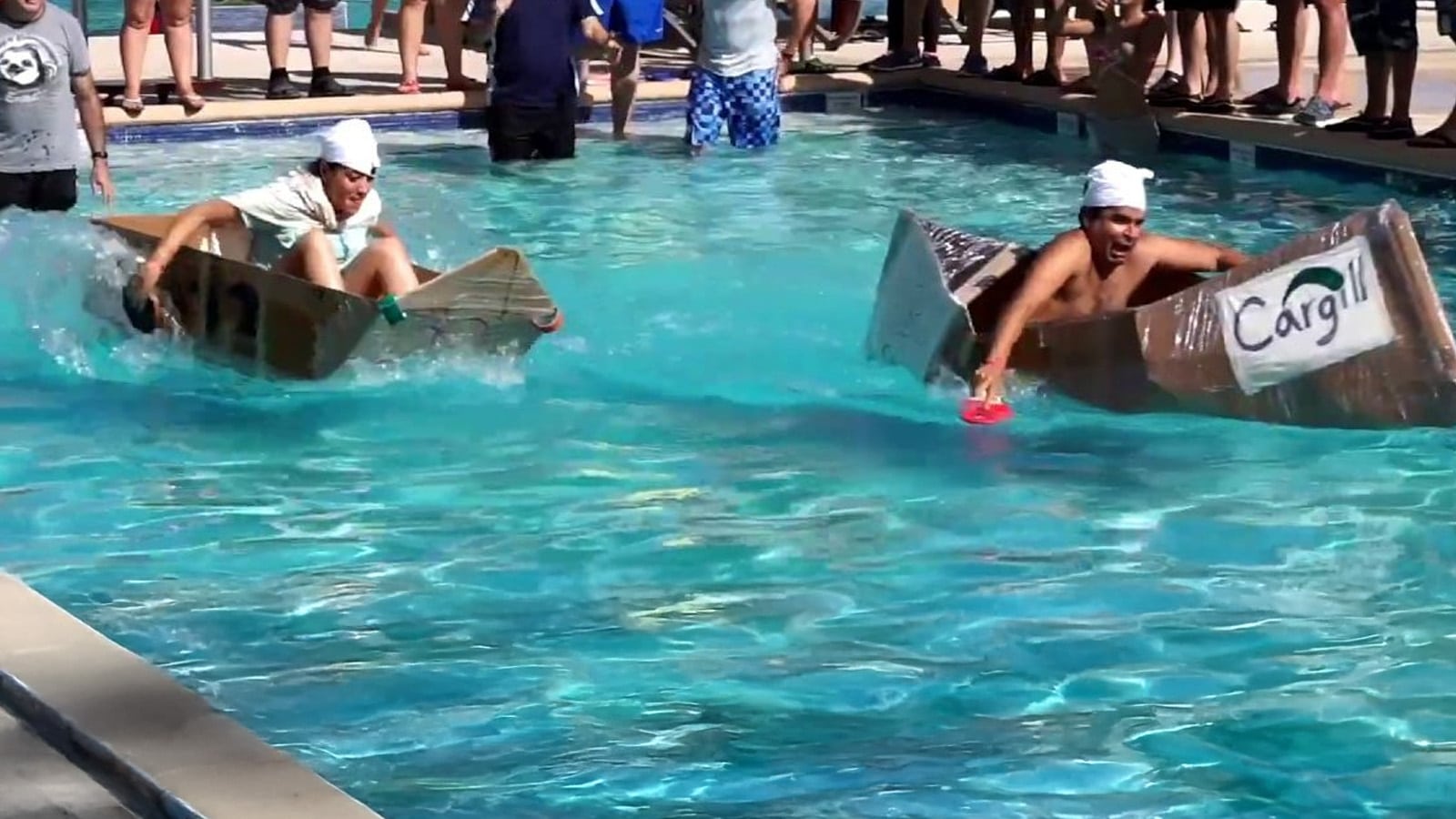 Students racing cardboard boats in the pool